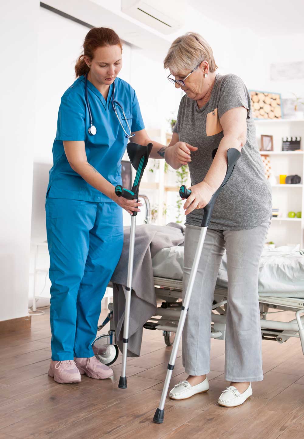 Nurse helping a patient on crutches with rehabilitation in the home